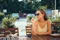 Young woman waiting for her friends at outdoor cafe, turning to the side