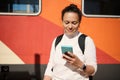 Young woman waiting train, using smart phone, checks mobile app, booking online tickets on internet. Railroad transport Royalty Free Stock Photo