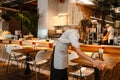 Young woman waitress disinfecting table in restaurant