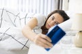 Young woman using mobile phone on bed Royalty Free Stock Photo