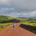 Young woman walk at country road. Fields with blue sky. Terceira