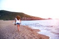 Young woman walk on an empty wild beach towards celestial beams of light falling from the sky Royalty Free Stock Photo