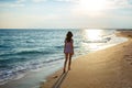 Young woman walk on an empty wild beach towards celestial beams of light falling from the sky, Royalty Free Stock Photo