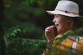 Young woman on a walk outdoors in forest in summer nature, eating spruce shoots.