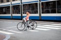 Young woman walking across a crosswalk with a bicycle in Amsterdam Netherlands (Holland) Europe