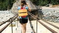 Young woman walking across the wooden bridge over mountain river Royalty Free Stock Photo