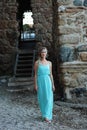 Young woman walking against blurred background of medieval stone Royalty Free Stock Photo
