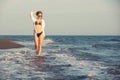 Young woman walking along sea or ocean beach at sunset Royalty Free Stock Photo