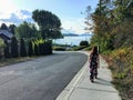 A young woman walking along the sidewalk towards the ocean in the distance. It is a beautiful neighbourhood on a pretty sunny day Royalty Free Stock Photo