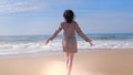 Woman walking with arms up on beach, lens flare effects