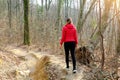 Young woman walking away alone on a forest path wearing a red down jacket in autumn winter Royalty Free Stock Photo