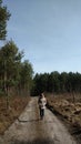 Young woman walking away alone on a forest path wearing sunglasses. Early spring time in march Royalty Free Stock Photo