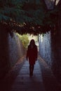 Woman walking away down a dark alley