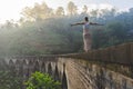 Young woman walking on balance on the Famous Nine Arch Bridge in Demodara, Sri Lanka during sunrise