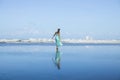 Young woman walking barefoot on the beach. Full body portrait. Slim Caucasian woman wearing long dress. Enjoy time on the beach.