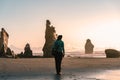 Young woman walking by the beach between big rock formations. Inspirational and travel concept