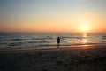 Young woman walking on beach under sunset light