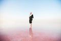 Young woman walking on Dead Sea with beautiful sky at pink sunrise Royalty Free Stock Photo