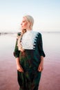 Young woman walking on Dead Sea with beautiful sky at pink sunrise Royalty Free Stock Photo