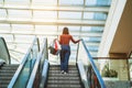 Young woman is walking on the escalator in a mall and shopping Royalty Free Stock Photo