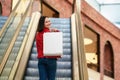 Young woman is walking on the escalator in a mall and shopping with a happy smile Royalty Free Stock Photo