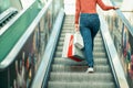 Young woman is walking on the escalator in a mall and shopping Royalty Free Stock Photo