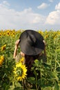 Young woman walking in the field with sunflowers. Beautiful young girl enjoying nature on the field of sunflowers at sunset Royalty Free Stock Photo