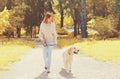 Young woman walking with her Golden Retriever dog on leash in sunny autumn Royalty Free Stock Photo