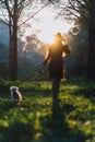 Young woman walking her pet dog on a lush green meadow in a forest setting Royalty Free Stock Photo