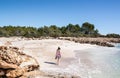 Young woman walking on an idyllic white sand beach on the Mediterranean coast.