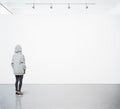 Young woman walking in modern gallery and looking at the blank canvas. Square Royalty Free Stock Photo