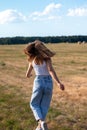 Young woman walking in an open field, her long, dark hair blowing in the wind Royalty Free Stock Photo