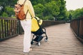 Young woman walking in park with baby stroller Royalty Free Stock Photo