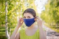 A young woman is walking in the park and putting on a medical mask on her face. Royalty Free Stock Photo