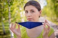 A young woman is walking in the park and putting on a medical mask on her face. Royalty Free Stock Photo