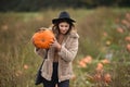 Young woman walking with a pumpkin in a picturesque field