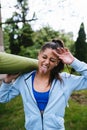 Young woman walking in urban park holding fitness rug. Royalty Free Stock Photo