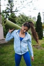 Young woman walking in urban park holding fitness rug. Royalty Free Stock Photo