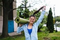 Young woman walking in urban park holding fitness rug. Royalty Free Stock Photo