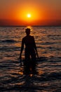 Young woman walking on water at sunset. Sunset and silhouette of a young woman as she emerges from the water. Royalty Free Stock Photo