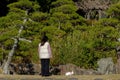 Young woman walking a white rabbit on a red leash in Kasai Rinkai Park, near a tranquil pond Royalty Free Stock Photo
