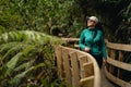 Young woman walking by wooden bridge surrounded by new zealand native vegetation Royalty Free Stock Photo