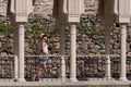 Young woman walks along colonnade in antique city. Historical sites