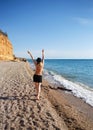 Young woman walks along the sea barefoot on the sand. back view Royalty Free Stock Photo