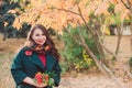 A young woman walks in the autumn Park. Brunette woman wearing a green coat. She is holding a bouquet of yellow leaves