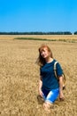 A young woman walks through a golden wheat field. Summer sunny day, the sun is shining brightly. Healthy lifestyle. Good mood Royalty Free Stock Photo