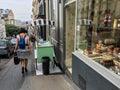 Young woman walks past bakery show window on Montmartre in Paris, France