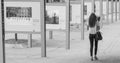 Young woman walks past an outdoor photo exhibit