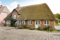 A young woman walks past a typical thatched-roof country house in a Danish village Royalty Free Stock Photo