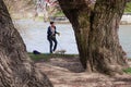 Young woman walks a small, white dog near the river